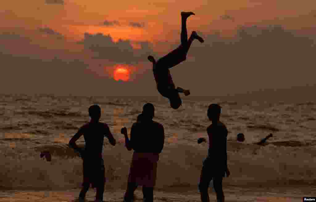 Seorang anak laki-laki melakukan atraksi jungkir balik di pantai saat matahari terbenam di Kolombo, Sri Lanka.