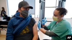 Brian Kennedy, an elementary school physical education teacher, gets a COVID-19 vaccination during a mass vaccination of 1,000 employees of Denver Public Schools Feb. 13, 2021, in Denver, Colo.