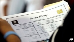 FILE - A job applicant looks at job listings for the Riverside Hotel at a job fair hosted by Job News South Florida, in Sunrise, Fla.