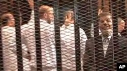 FILE - Image made from video provided by Egypt's Interior Ministry shows ousted President Mohammed Morsi, right, speaking from the defendant's cage as he stands with co-defendants in a makeshift courtroom during a trial hearing in Cairo, Nov. 4, 2013. 