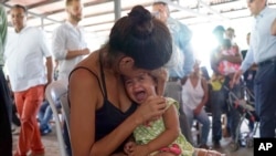 FILE - A Venezuelan woman holds a girl at a health post for migrants in Cucuta, along Colombia's border with Venezuela, July 16, 2018. 