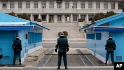 FILE - A North Korean soldier, center top, looks at South Korean soldiers at Panmunjom, March 12, 2014. 