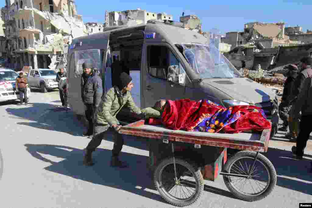 A man pushes a cart with a woman lying on it as vehicles wait to evacuate people from a rebel-held sector of eastern Aleppo, Syria Dec. 15, 2016. 