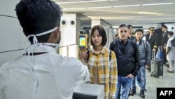 Petugas kesehatan memeriksa penumpang yang baru tiba di bandara Chandra Bose, Kolkata, India, Selasa (21/1) untuk mendeteksi kemungkinan terjangkit virus corona. 