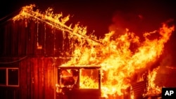Flames from a wildfire shoot from a home in the Berry Creek area of Butte County, California, Sept. 9, 2020. 