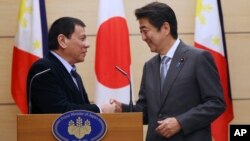 PM Jepang Shinzo Abe (kanan) dan tamunya Presiden Filipina Rodrigo Duterte berjabat tangan sebelum memberikan konferensi pers bersama di Tokyo, Rabu (26/10).