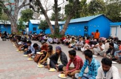 Daily wage workers and homeless people eat food inside a government-run night shelter during a 21-day nationwide lockdown to limit the spreading of coronavirus disease (COVID-19), in the old quarters of Delhi, India, March 26, 2020.