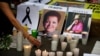 FILE - A woman places a candle in front of pictures of slain journalists Miroslava Breach, left, and Javier Valdez during a demonstration against the killing of journalists, outside the Interior Ministry in Mexico City, May 16, 2017.