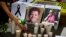 FILE - A woman places a candle in front of pictures of slain journalists Miroslava Breach, left, and Javier Valdez during a demonstration against the killing of journalists, outside the Interior Ministry in Mexico City, May 16, 2017.