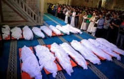Mourners pray over the bodies of 17 Palestinians who were killed in overnight Israeli airstrikes in Gaza City, May 16, 2021.