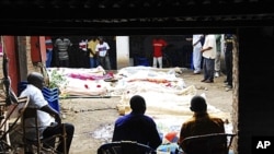 People sit near bodies of relatives killed after gunmen burst into a bar in Gatumba, Bujumbura Rural Province, Burundi, Sept. 19, 2011 (file photo).