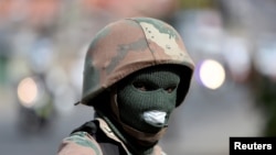 FILE - A member of the South African National Defense Force looks on during a patrol in an attempt to enforce a nationwide lockdown, aimed at limiting the spread of the coronavirus disease, in Alexandra township, South Africa, March 28, 2020.