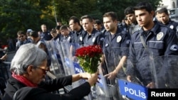A demonstrator holds flowers before a police barricade during a commemoration for the victims of Saturday's bomb blasts in Ankara, Turkey, October 11, 2015.