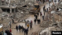 গাজা সিটিতে ইসরায়েলি হামলায় বিধ্বস্ত ভবনের ধ্বংসাবশেষের পাশ দিয়ে হেঁটে যাচ্ছে ফিলিস্তিনিরা। ফটোঃ ৬ ফেব্রুয়ারি, ২০২৫।