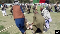A wounded man is carried away following explosions at an agrucultural show in Lashkar Gah, Helmand province, southern Afghanistan, March 23, 2019.