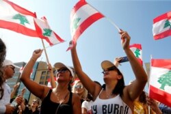 Demonstrators wave national flags during an anti-government protest in Beirut, Lebanon, Oct. 19, 2019.