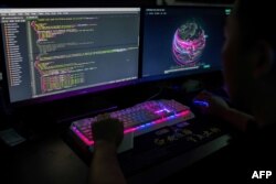 Seorang anggota kelompok peretasan Red Hacker Alliance yang menolak memberikan nama aslinya, menggunakan situs web yang memantau serangan siber global di komputernya di kantor mereka di Dongguan, China. (Foto: AFP)