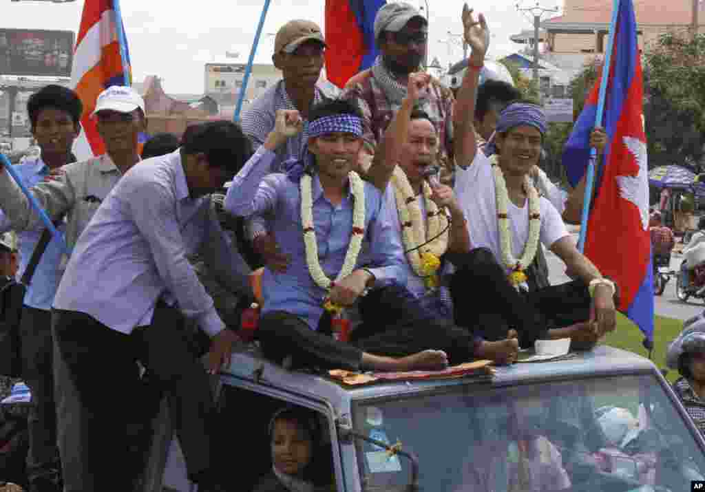 Anti-government protesters who had been in prison since their arrest in January wave from atop a truck during a rally in Phnom Penh, Cambodia, May 30, 2014.