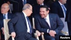 Saad al-Hariri talks with Lebanese President Michel Aoun while attending a military parade to celebrate the 74th anniversary of Lebanon's independence in downtown Beirut, Lebanon, Nov. 22, 2017.