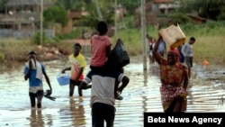 People cross a section of Pemba, a city that remains flooded on the northeastern coast of Mozambique, May, 2, 2019. 