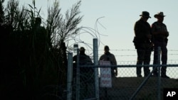 FILE - Texas troopers stand near a "No Trespassing" sign and concertina wire along the banks of the Rio Grande at Shelby Park, Aug. 1, 2023, in Eagle Pass, Texas. 