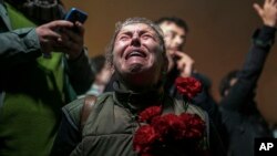 A woman cries as she and others gather in a moment of silence to mark the first anniversary of the country's catastrophic earthquake, in Antakya, Turkey, on Feb. 6, 2024.