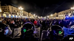 Police face people protesting new government restrictions to curb the spread of the coronavirus, in Turin, Italy, Oct. 26, 2020.