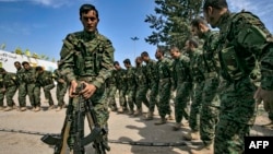 Fighters of the U.S.-backed Kurdish-led Syrian Democratic Forces (SDF) dance as they celebrate near the Omar oil field in the eastern Syria, March 23, 2019, after announcing the total elimination of the Islamic State group's last bastion.