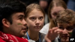 Climate activist Greta Thunberg, center, talks with other climate activists youth at the COP25 climate talks summit in Madrid, Dec. 6, 2019. 