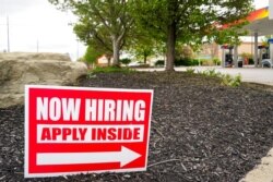 FILE - Hiring signs are posted outside a gas station in Cranberry Township, Butler County, Pa., May 5, 2021.