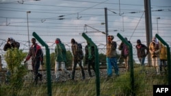 Migrants who successfully crossed the Eurotunnel terminal walk on the side of the railroad as they try to reach a shuttle to Great Britain, July 28, 2015 in Frethun, northern France.