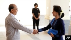 Myanmar President Thein Sein, left, shakes hands with Myanmar opposition leader Aung San Suu Kyi as they meet at Myanmar Presidential Palace in Naypyitaw, Myanmar, Oct 31, 2014. 