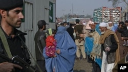 A policeman looks on as passengers wait to cross the Pakistan-Afghanistan border on foot in the northwest town of Torkham, November 27, 2011.