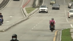 A food delivery rider tries to save time by traveling down a lane in the wrong direction. (VOA/Dave Grunebaum)