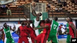 FILE - A player from Kano Pillars, center, in green and white, jumps to make a basket, challenged by Mark Mentors players in red and black, during Nigeria's Final Four in Lagos, Nigeria, Sept. 5, 2013.