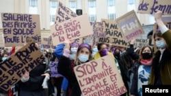 FILE - Women hold placards during a demonstration to call for gender equality and demand an end to violence against women, on International Women's Day in Brussels, Belgium, March 8, 2021. 
