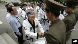 FILE - Korean-American taekwondo grandmaster Jung Woo-jin, center, shakes hands with North Korean border soldiers as he offers a peace gesture of taekwondo "dobok" robes on the North Korean side of the DMZ line outside Panmunjom, May 19, 2006.