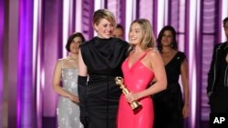 En esta imagen proporcionada por CBS, la directora Greta Gerwig, izquierda, y la actriz Margot Robbie reciben el premio al logro cinematográfico y de taquilla por “Barbie” en los Globos de Oro el domingo 7 de enero de 2024, en el Hotel Beverly Hilton en Beverly Hills, California.