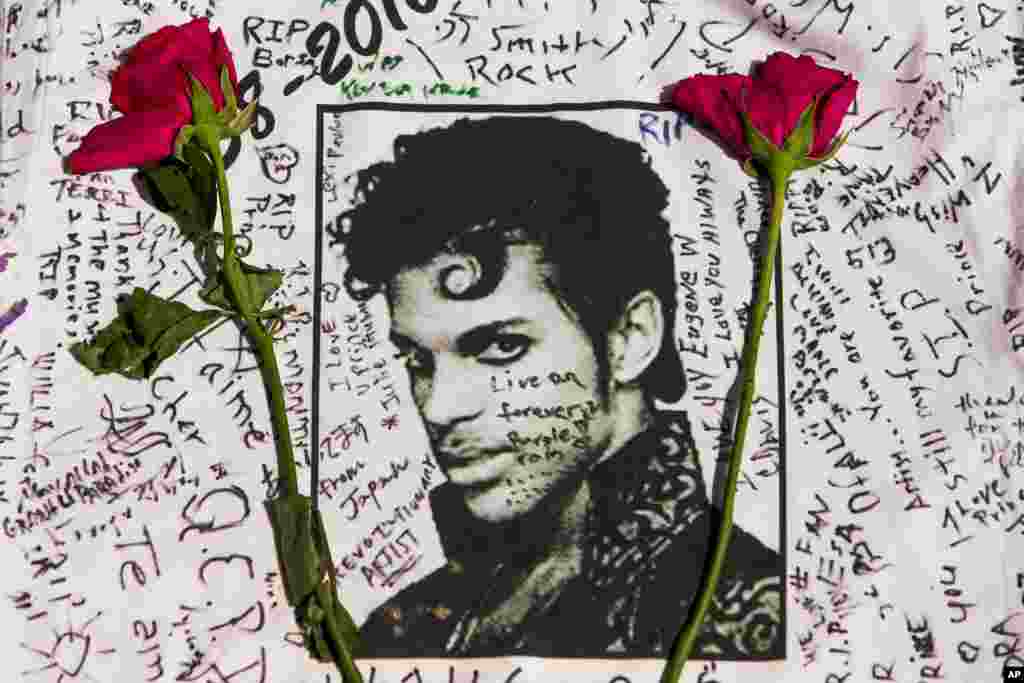 Flowers lay on a T-shirt signed by fans of singer Prince at a makeshift memorial place created outside Apollo Theatre in New York, April 22, 2016.