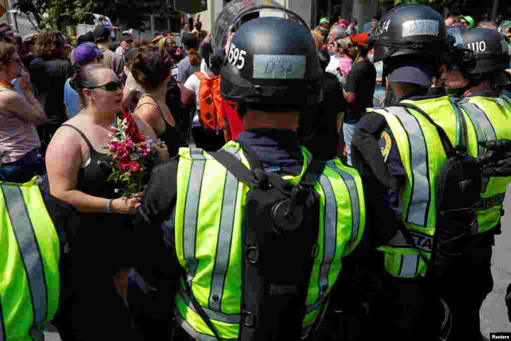 Police in riot gear block demonstrators at the site where Heather Heyer was killed, on the one year anniversary of 2017 Charlottesville "Unite the Right" protests, in Charlottesville, Virginia, Aug. 12, 2018. 