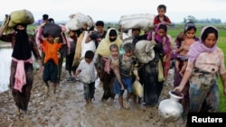 A group of Rohingya refugees walk on the muddy road after traveling over the Bangladesh-Myanmar border in Teknaf, Bangladesh, Sept. 1, 2017.