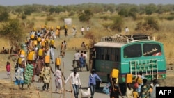 Internally displaced people carry water from outside as they walk toward the entrance of a United Nations Mission in the Republic of South Sudan base in Malakal, Feb. 6, 2014.