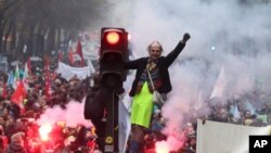 A man stands on a traffic light during a demonstration in Paris, Dec. 5, 2019.
