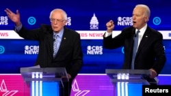 Democratic 2020 U.S. presidential candidates Senator Bernie Sanders and former Vice President Joe Biden talk at the tenth Democratic 2020 presidential debate at the Gaillard Center in Charleston, South Carolina, Feb. 25, 2020.