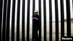 Jorge Alverez of Mexico crosses the wall border between Mexico and the United States at the beach of Tijuana, Mexico May 6, 2006. REUTERS/Carlos Barria