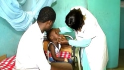 FILE - A boy suffering from side effects after receiving a measles vaccine, accompanied by his father, is checked by a nurse at Ebolowa regional hospital, in Ebolowa, Cameroon, Dec. 9, 2019. (Moki Edwin Kindzeka/VOA)