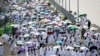 Para jemaah haji membawa payung untuk melindungi dari terik matahari, tiba di pemondokan jemaah, tenda Mina, di tengah pelaksanaan ibadah Haji di dekat Makkah, Jumat, 14 Juni 2024. (Foto: Fadel Senna/AFP)