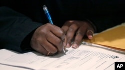 FILE - A job seeker fills out an application during a National Career Fairs job fair, in Chicago, Illinois. A tightening job market in Canada means international students in Canada are having difficulty finding work.