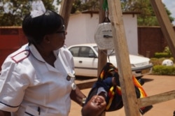 A nurse weighs a child at a health clinic in Malawi's capital, Lilongwe. Heath experts fear a coronavirus lockdown would intensify hunger among the country's poor. (Lameck Masina/VOA)