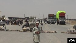FILE - A boy stands at the closed Chaman border crossing between Pakistan and Afghanistan with trucks seen stranded in the background.